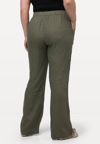 Pantalons larges vert olive en tissu léger avec une taille élastique et des poches latérales, présentant une surface lisse et texturée.