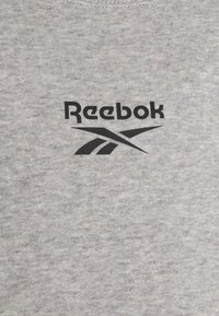 Sweatshirt gris en matière douce, avec un logo et des graphiques Reebok noirs sur le devant. Design simple avec un col rond classique.
