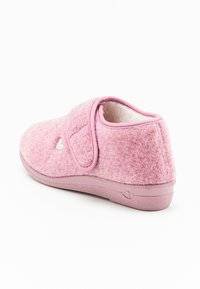 Pantofole di feltro rosa con una fascetta in Velcro, forma arrotondata, superficie texturizzata, interno morbido e un piccolo dettaglio decorativo a forma di cuore.
