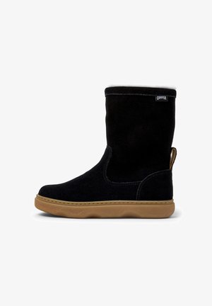 Botte mi-mollet en daim noir avec semelle en caoutchouc beige, tirette au niveau du talon et petite étiquette de la marque Camper près du bord supérieur.