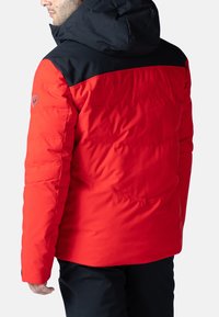 Roter Puffermantel mit schwarzer Kapuze, der eine glatte Textur, ein gestepptes Design und ein Logo am Ärmel aufweist. Verstellbarer Saum und stilvolle Nähte.