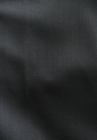 Tejido negro con una textura suave, que muestra un brillo sutil. El material está tejido de manera apretada, ofreciendo un patrón consistente en toda la superficie.