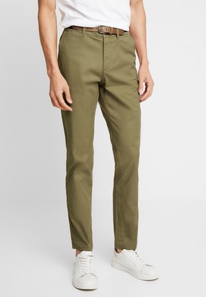 Khakifärgade chinos i bomull med slim fit-design, utrustade med sidfickor, ett brunt bälte och vita sneakers. Slät textur och flat front.