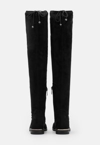 Botas negras por encima de la rodilla en suave ante, con punta redonda, parte superior ajustable con cordón y detalles en metal plateado cerca de los tobillos.