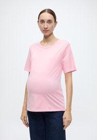 Ροζ βαμβακερό μπλουζάκι εγκυμοσύνης με κοντά μανίκια, στρογγυλή λαιμόκοψη και άνετη εφαρμογή, σχεδιασμένο για να χωράει την αναπτυσσόμενη κοιλιά.