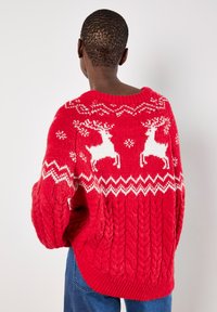 Roter Strickpullover mit weißen Elchmustern und Zickzackakzenten. Verfügt über eine dicke Kabelstrickstruktur und einen runden Ausschnitt.