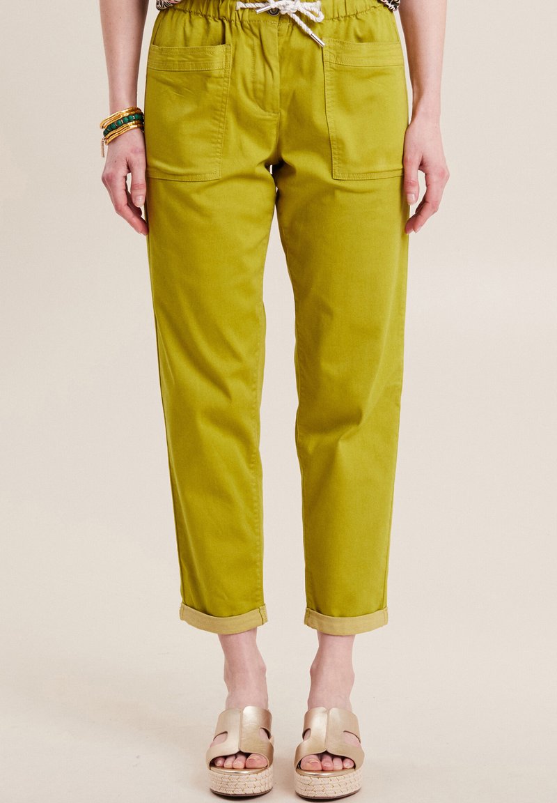 Groene katoenen joggerbroeken van een katoenmix met een elastische tailleband, twee voorzakken en opgerolde manchetten, gecombineerd met gouden instapsandalen.
