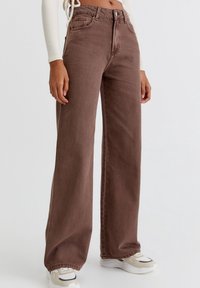 Ruske leve široke hlače iz bombaža, z visokim pasom, dvema sprednjima žepoma in rahlim bledenjem. V kombinaciji z belimi in bež supergami.