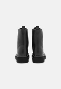 Botines de cuero negro con un diseño elegante, que presentan una textura suave, lengüeta para tirar y una suela gruesa de goma para tracción.