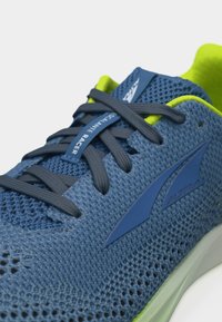 Κοντινή λήψη του μπλε και νέον πράσινου παπουτσιού τρεξίματος Altra Escalante Racer με άνω μέρος από διχτυωτό υλικό και σκουρό μπλε κορδόνια.