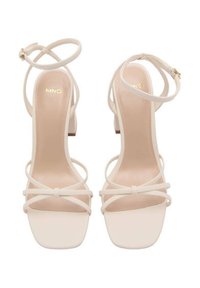 Beige High-Heelsandalen mit dünnen, überkreuzten Riemen, quadratischer Zehenform und glatter Oberfläche. Mit einem kleinen Blockabsatz.