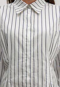 Witte button-up shirt met smalle marineblauwe verticale strepen, een puntige kraag en een gladde katoenstof met een ontspannen pasvorm.