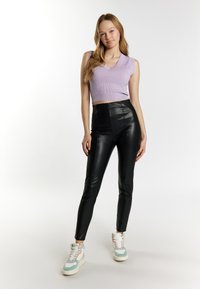 Lilla ribbet cropped top med v-hals, parret med højtaljede sorte læderbukser og pastelfarvede sneakers med grønne og pink detaljer.
