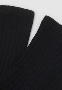 Calzini neri a costine con una texture morbida, caratterizzati da un design aderente e da polsini lisci. Le costine creano un motivo sottile sulla stoffa.