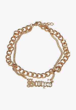 Guldfarvet kædetrøje med sammenkoblede store og små led, samt en dekorativ vedhæng med ordet "Sour."