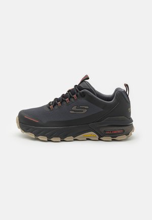 Black waterproof sneaker with a textured synthetic upper, elastic laces, and a rubber outsole featuring prominent tread patterns and branding.
