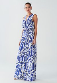 Maxi haljina s dubokim dekolteom, izrađena od laganog tkanja s plavo-bijelim apstraktnim uzorkom. Na struku je vezana radi naglašenog silueta.