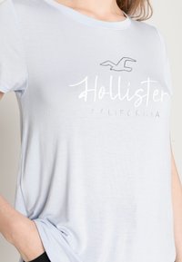 Jasnoniebieska koszulka krótki rękaw z okrągłym dekoltem. Posiada haftowane logo "Hollister" oraz "California" w białym i srebrnym kolorze.