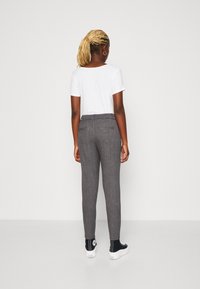 Grå, texturerade byxor med slim fit, med midjeband och två bakfickor, i kombination med en enfärgad vit skjorta och svarta sneakers.