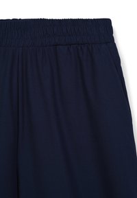 Pantalon de jogging bleu marine avec taille élastique, doté d'une texture lisse et d'un design simple, idéal pour une tenue décontractée ou pour se détendre.