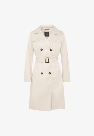 Trench-coat beige à double boutonnage avec larges revers, boutons en écaille de tortue, ceinture assortie avec boucle rectangulaire, et deux poches avant.