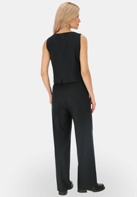 Czarny top bez rękawów w paski, w połączeniu z pasującymi spodniami o szerokich nogawkach, charakteryzującymi się eleganckimi liniami i smukłą sylwetką.