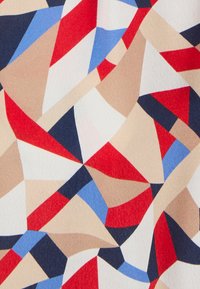 Multicolore stof met abstracte, geometrische vormen in rood, marineblauw, beige en lichtblauw, met een gladde, textuurovervlak.