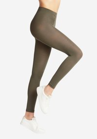 Olijfgroene leggings gemaakt van rekbaar materiaal met een hoge tailleband, gecombineerd met witte sneakers, die een slank, aansluitend ontwerp tonen.