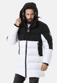 Gepolsterte Parka mit schwarzem Oberteil und weißem Unterteil. Verfügt über eine Kapuze, einen Frontreißverschluss und ein Logo-Patch am Ärmel. Strukturiertes, gestepptes Design.