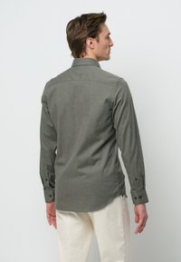 Groene button-up shirt met lange mouwen, textuurstof, subtiel patroon en afgeronde zoom. Draag met lichtgekleurde broeken.