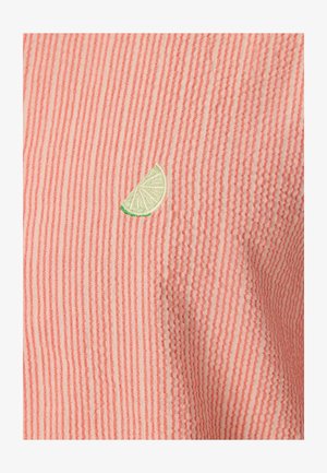 Tissu en seersucker rose et blanc avec de fines rayures verticales et un petit quartier de citron vert brodé près d'une couture.