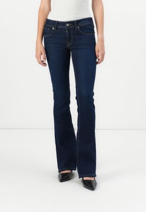 Dark blue flared jeans with a smooth texture, five pockets, and contrasting stitching. Paired with black pointed-toe heels.