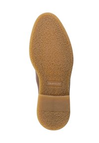 Bruine schoenzool met een gestructureerde, bruine rubberen onderkant en een lichtbeige accent. "TRAVELIN'" logo ingesmeed nabij de hak.