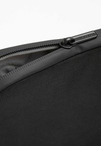 Borsa nera con zip, caratterizzata da un esterno texture e dotata di una zip liscia e di un interno foderato in grigio. Design compatto e funzionale.