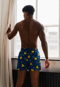 Boxer blu con motivo anatra e bolle, dotati di una vita elastica. Il tessuto sembra leggero e ha una texture liscia.