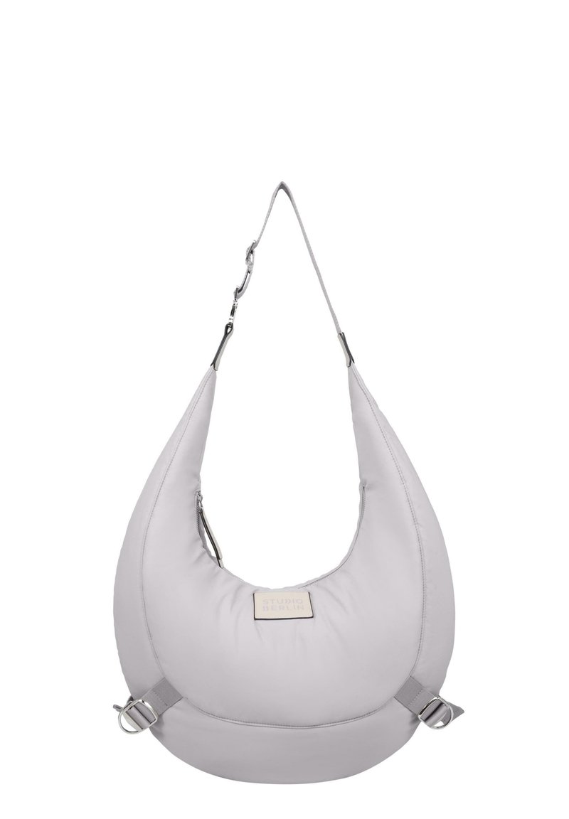 Lys grå hobo taske lavet af blødt materiale, med en bred rem, sølvhardware og et rektangulært mærke på forsiden.