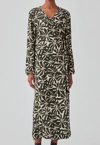 Langærmet omslagkjole med v-hals, fremstillet i et mørk olivengrønt stof prydet med et hvidt bladmønster og en længde til midt på læggen.