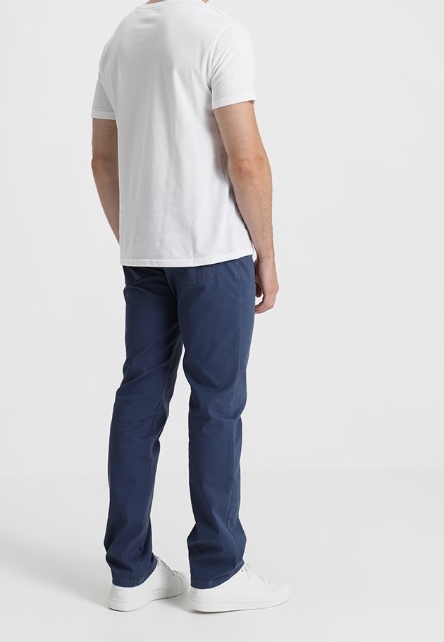 Chino bleu marine avec une coupe droite et une texture lisse, associé à un t-shirt blanc uni et des baskets blanches. Vue de dos visible.