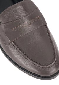 Donkerbruine leren loafers met gestikte details en een decoratieve accent aan de voorkant. Gladde textuur en rondtuit ontwerp.