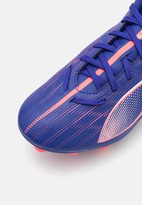 Lilla fotballsko med rosa detaljer, teksturert overdel og intrikat mønster. Har lisser og en fremtredende logo på siden.