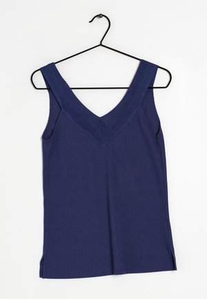 Débardeur côtelé bleu marine avec un profond décolleté en V, des larges bretelles et des fentes latérales, suspendu à un crochet en métal noir.