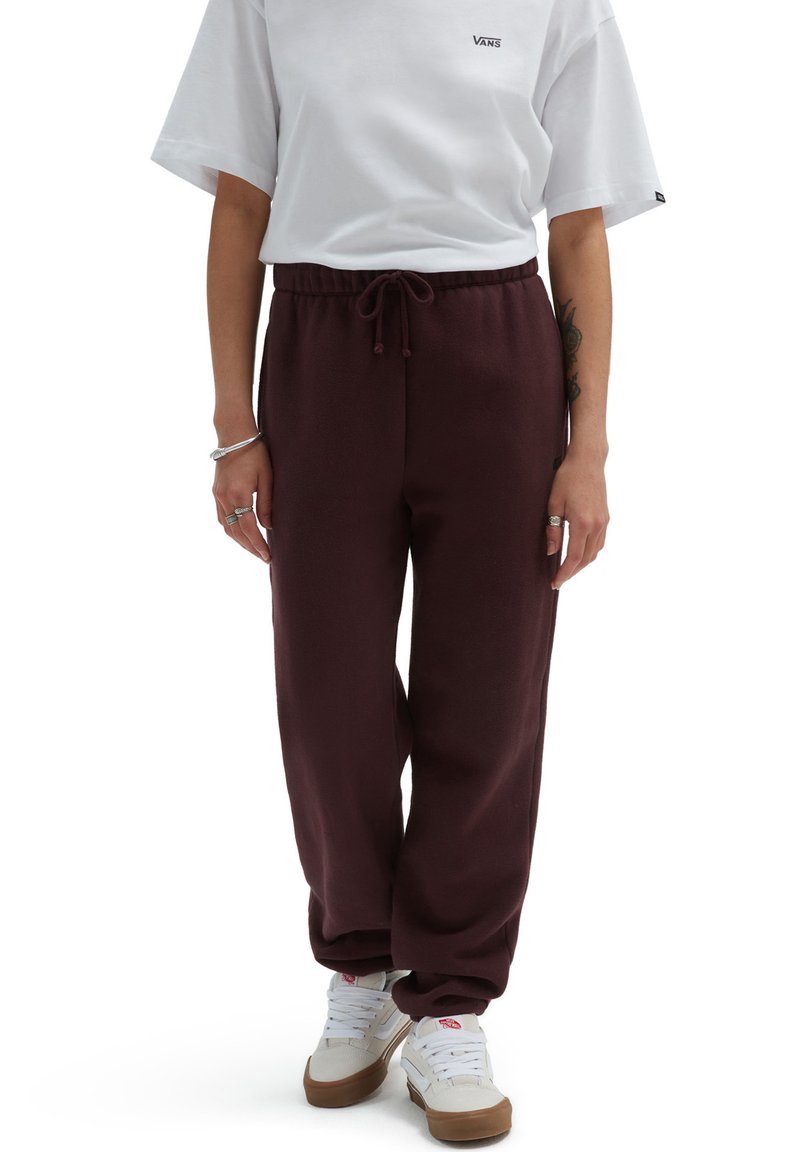 Bordeaux joggers met een trekkoord in de taille, omgeknoopte enkels en een zachte textuur, gecombineerd met een wit T-shirt met korte mouwen en sneakers.