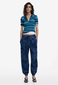 Striped short-sleeve polo shirt in blue tones, paired with loose blue denim joggers featuring an elastic waistband and side pockets.