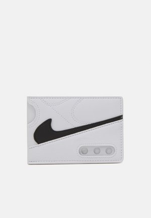 Cartera blanca hecha de material sintético, con un diseño de swoosh negro de Nike. Superficie texturizada con detalles de costura y tres recortes circulares.