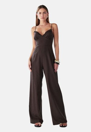 Bruin jumpsuit met een getailleerde bodice en wijde broekspijpen. Voorzien van dunne verstelbare bandjes en een overslagontwerp met lichte ruching.