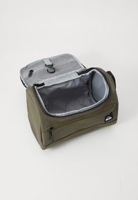 Olive green fabric bag with a gray interior, zipper closure, and mesh pocket. Contains a hook for hanging. Side logo detail present.