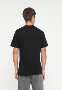 Black cotton t-shirt with a crew neckline and short sleeves. Fabric is smooth, fitted at the shoulders, with a clean back design.