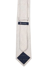 Beige gestructureerde stropdas van stof met een subtiele geweven patroon. Voorzien van een donkerblauw merklabel met witte letters, puntige punt ontwerp.