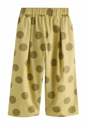 Voľné béžové nohavice s elastickým pásom a veľkými tmavozelenými bodkami po celej ploche.