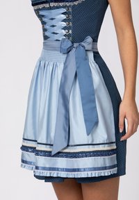 Blaues Kleid mit einem Pünktchenmuster. Verfügt über eine Satin-Schürze, Spitzenverzierungen, Schleifenakzente und ein eng anliegendes Oberteil mit Schnürdetails.